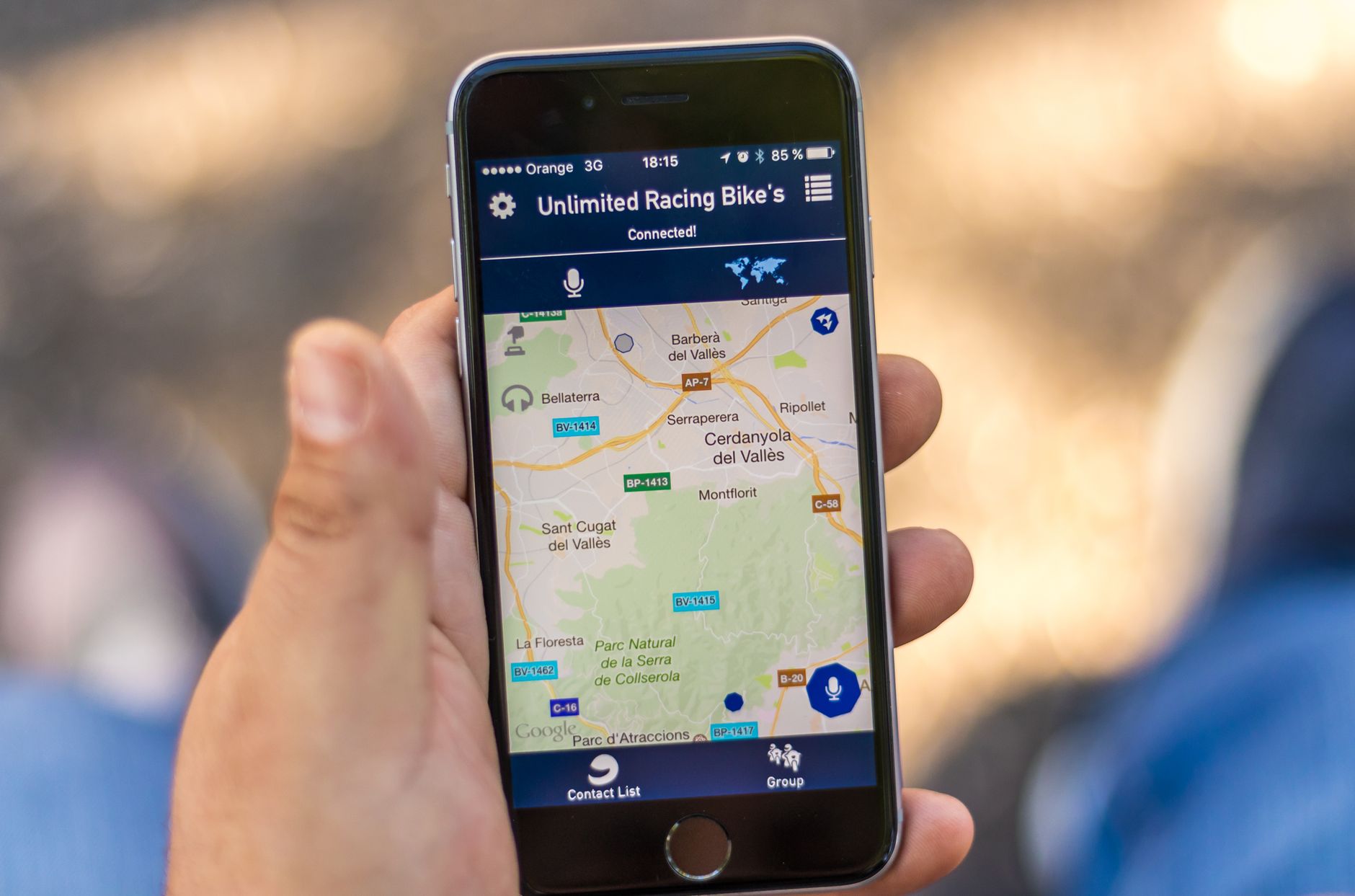 Person holding iPhone displaying Unlimited Racing Bike's app with map showing Catalan locations and Connected status