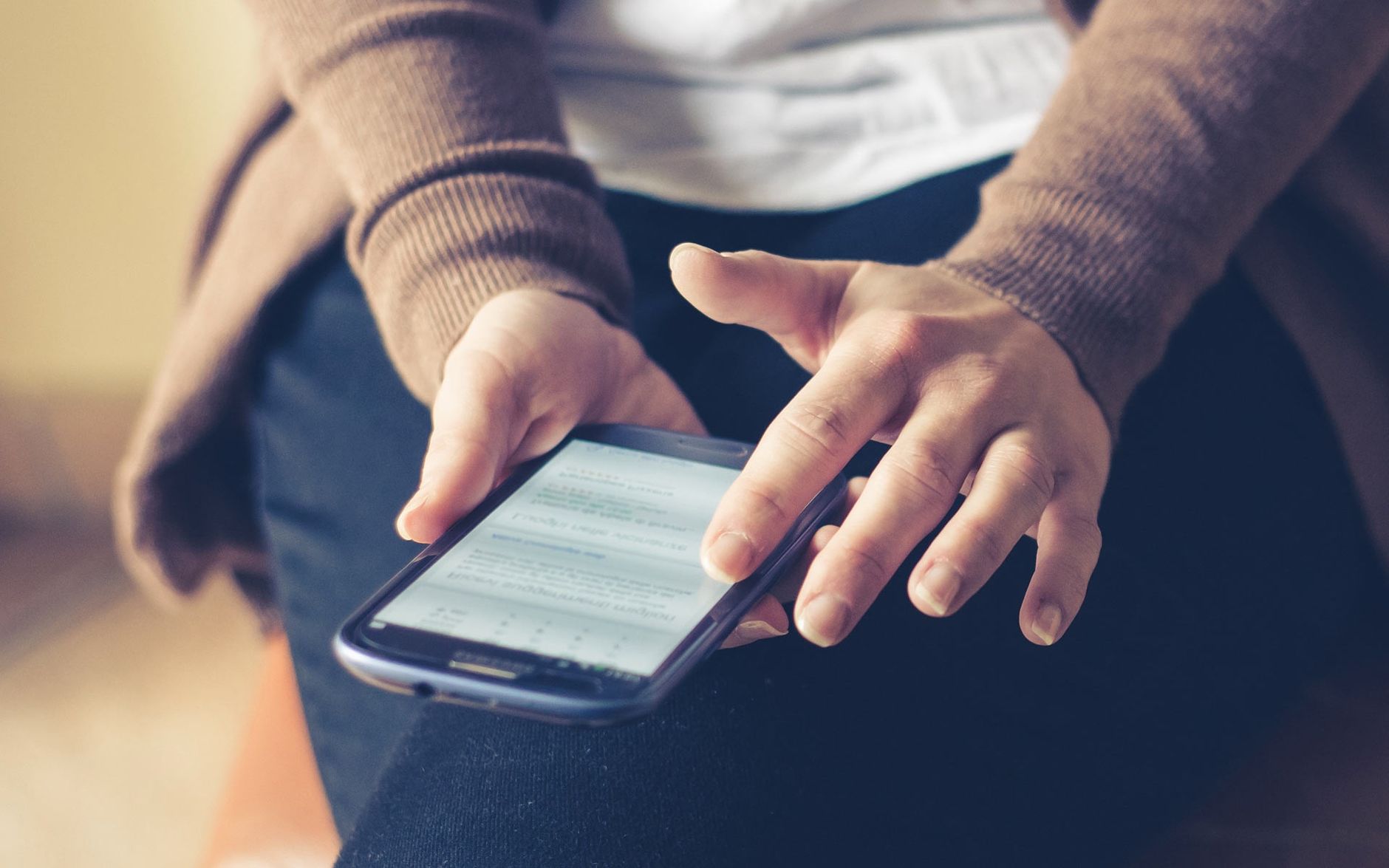 Close up of hands holding a smartphone displaying text on the screen