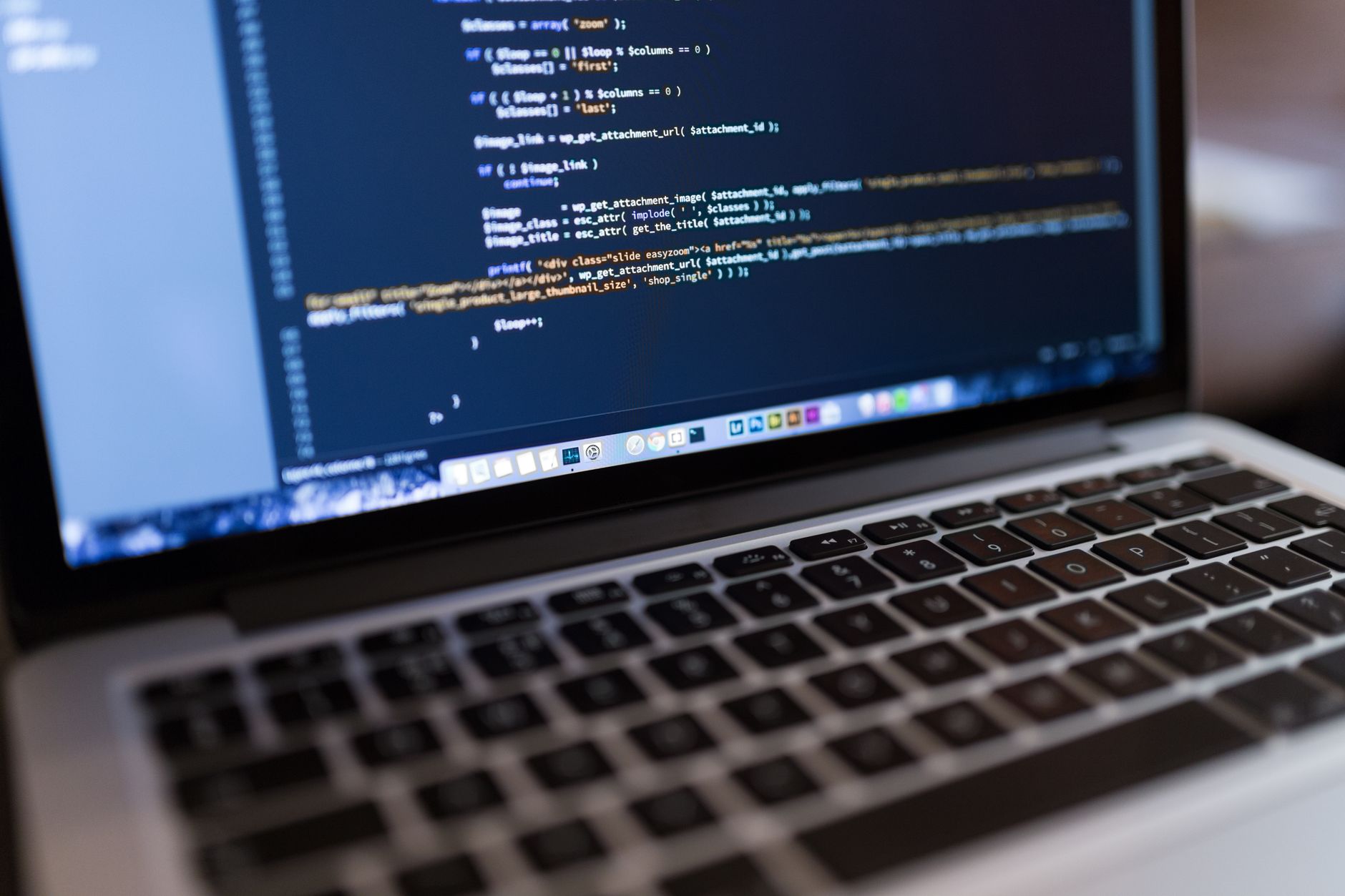 Laptop displaying PHP code in a text editor with syntax highlighting on a dark background