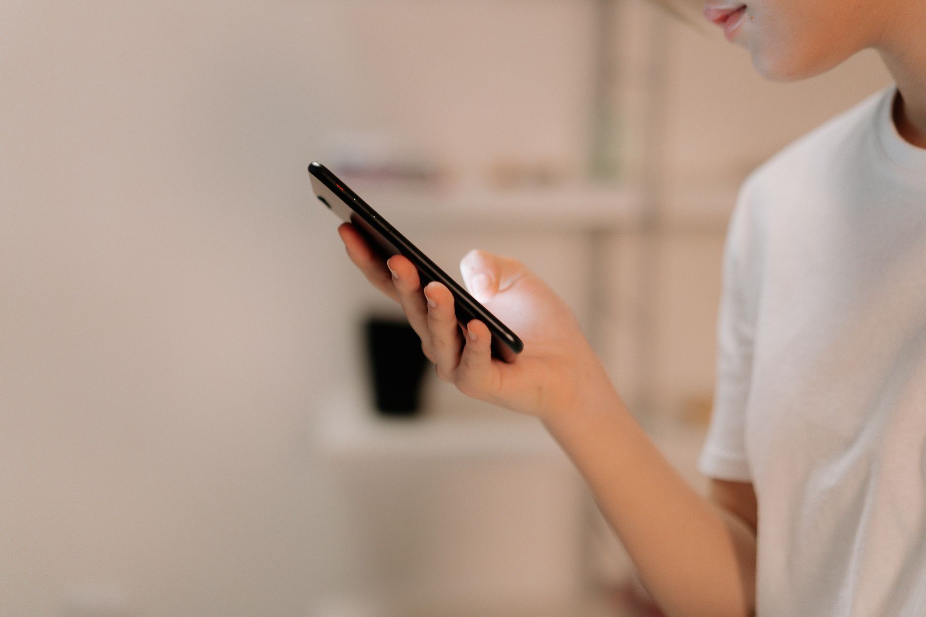Person in white shirt holding black smartphone with blurred background