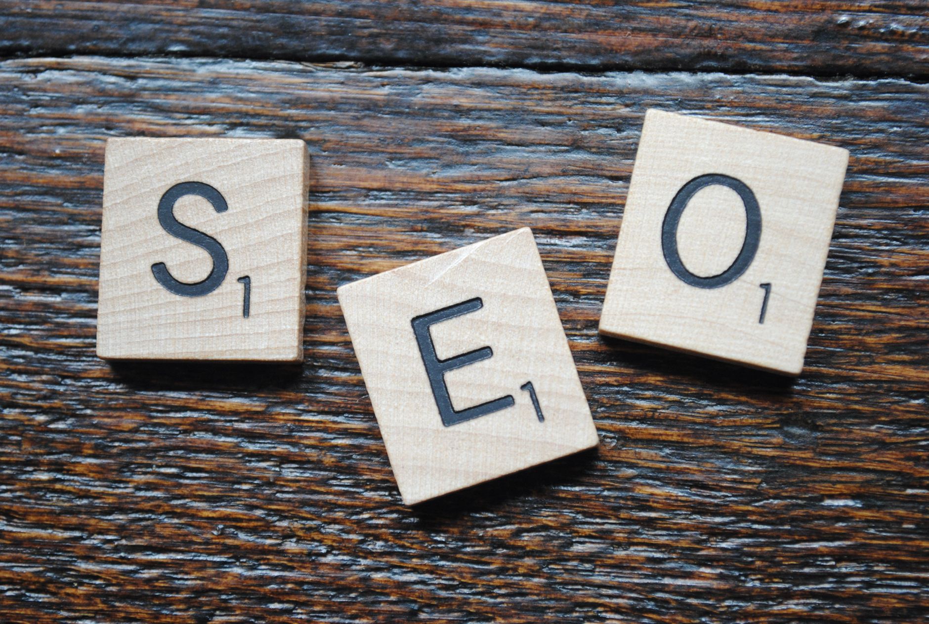 Three wooden Scrabble tiles spelling SEO on a weathered wood surface