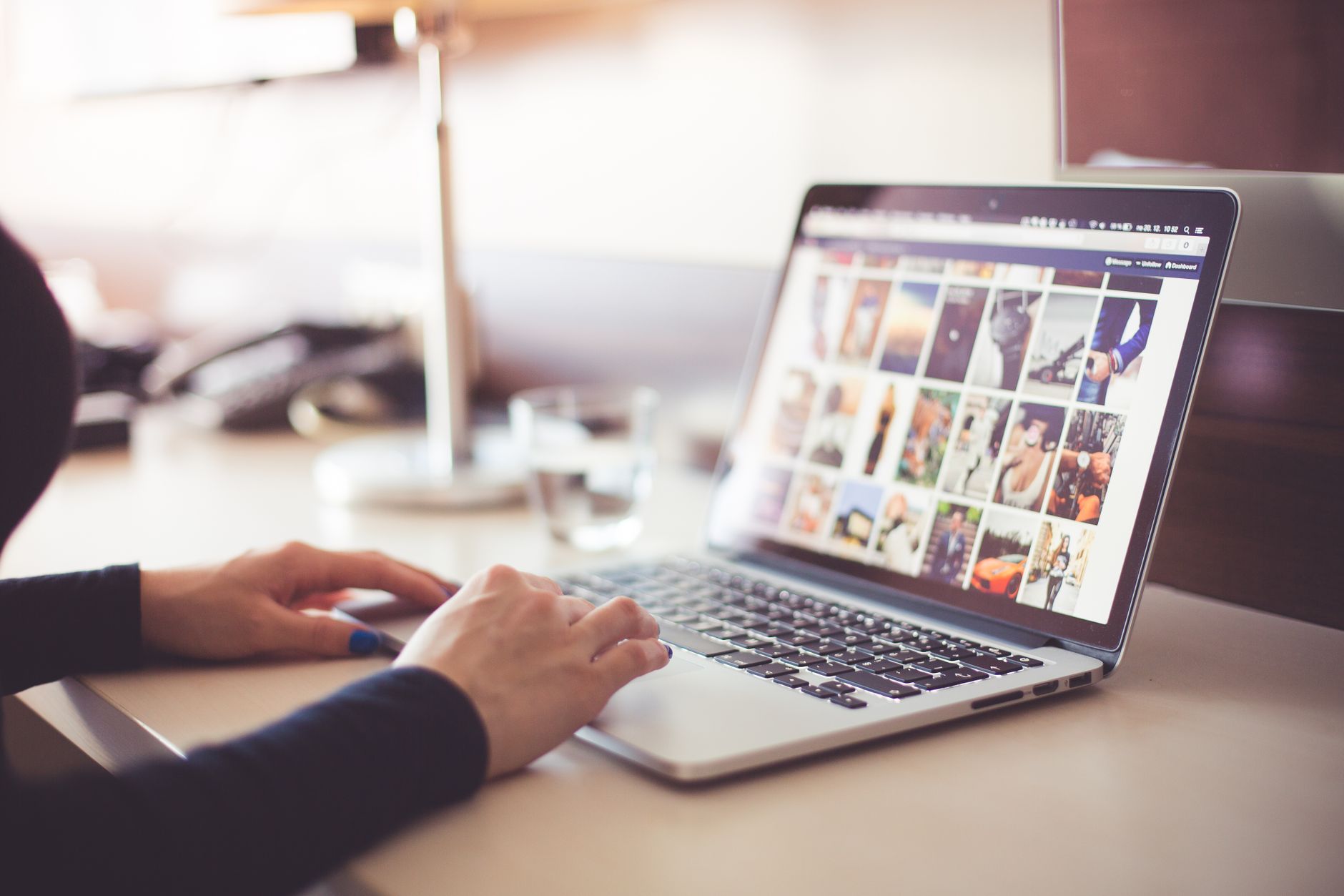 Person using laptop displaying a grid of colorful photos and images on the screen at a desk