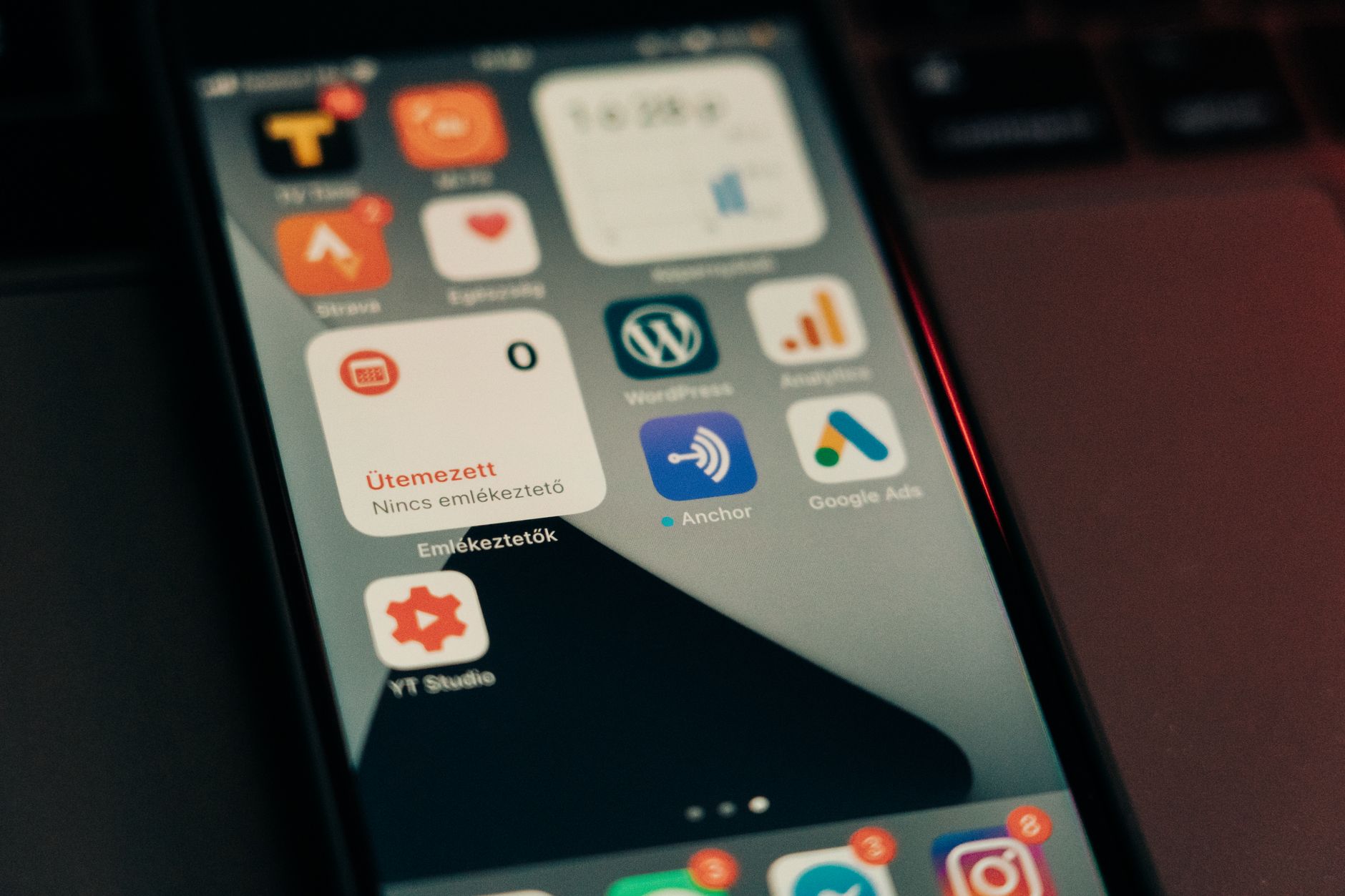Smartphone home screen displaying various app icons including WordPress, Google Ads, Anchor, and others with Hungarian text visible
