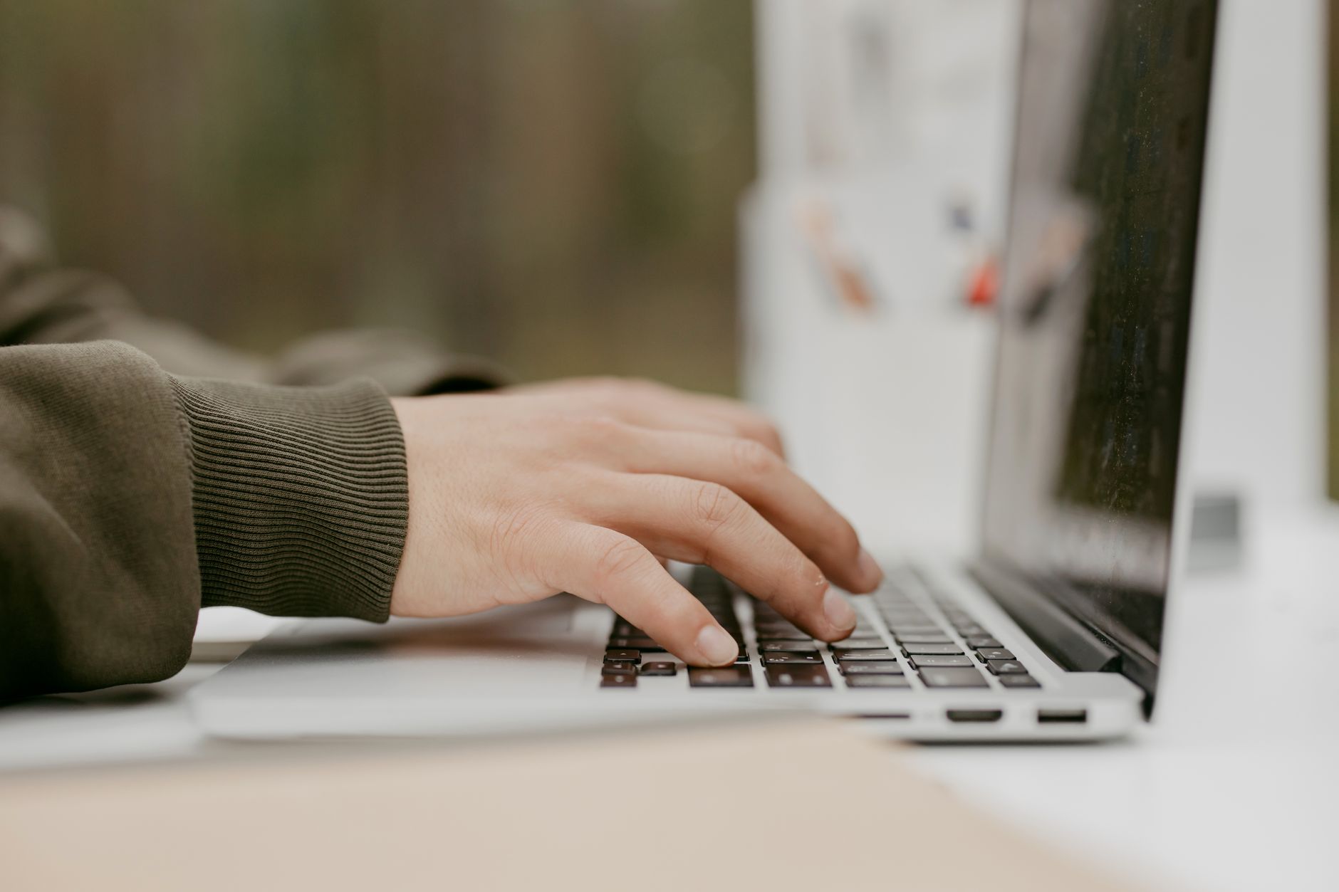 Child's hand typing on a laptop keyboard with blurred background