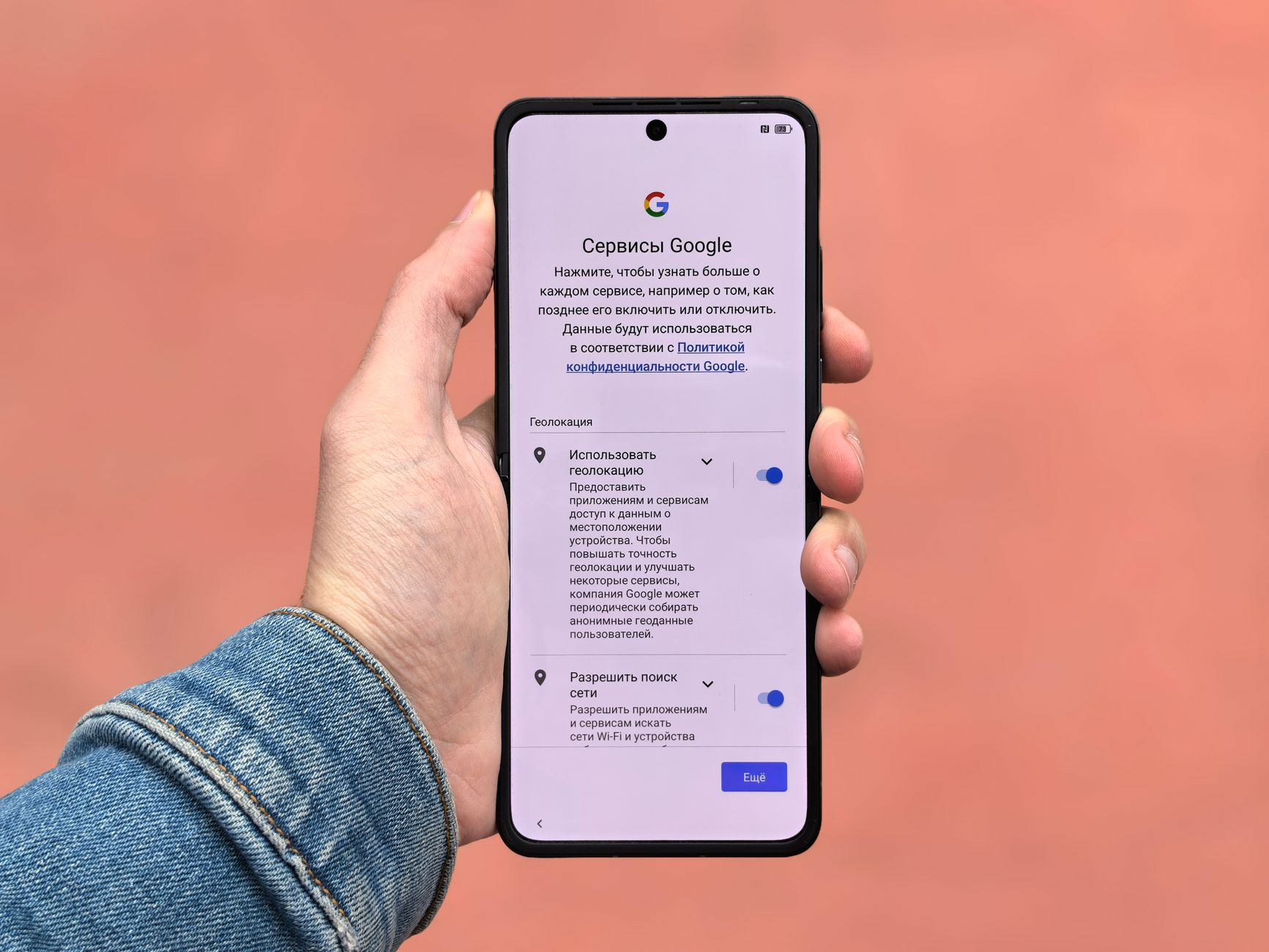 Hand holding a smartphone displaying Google Services settings page in Russian with geolocation and network search options