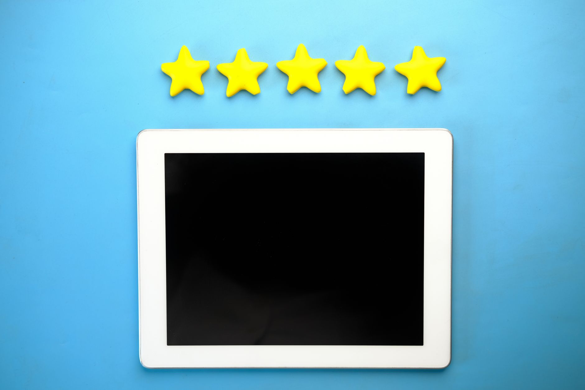 White tablet device with blank black screen below five yellow stars on blue background