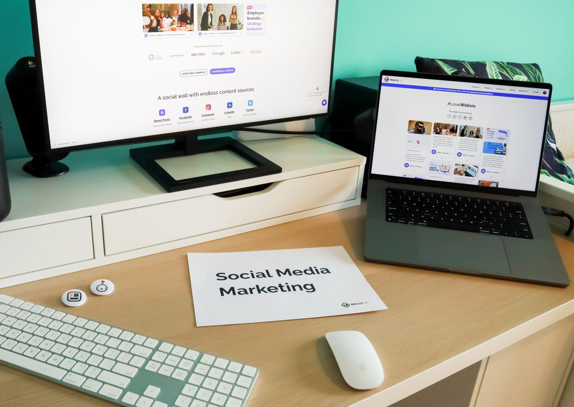 Desk workspace with desktop monitor, laptop, keyboard, mouse, and printed "Social Media Marketing" document with brand logos