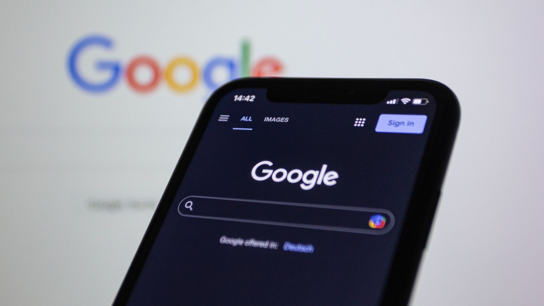 Google Search app on iPhone in dark mode with search bar, navigation tabs, and Sign in button visible