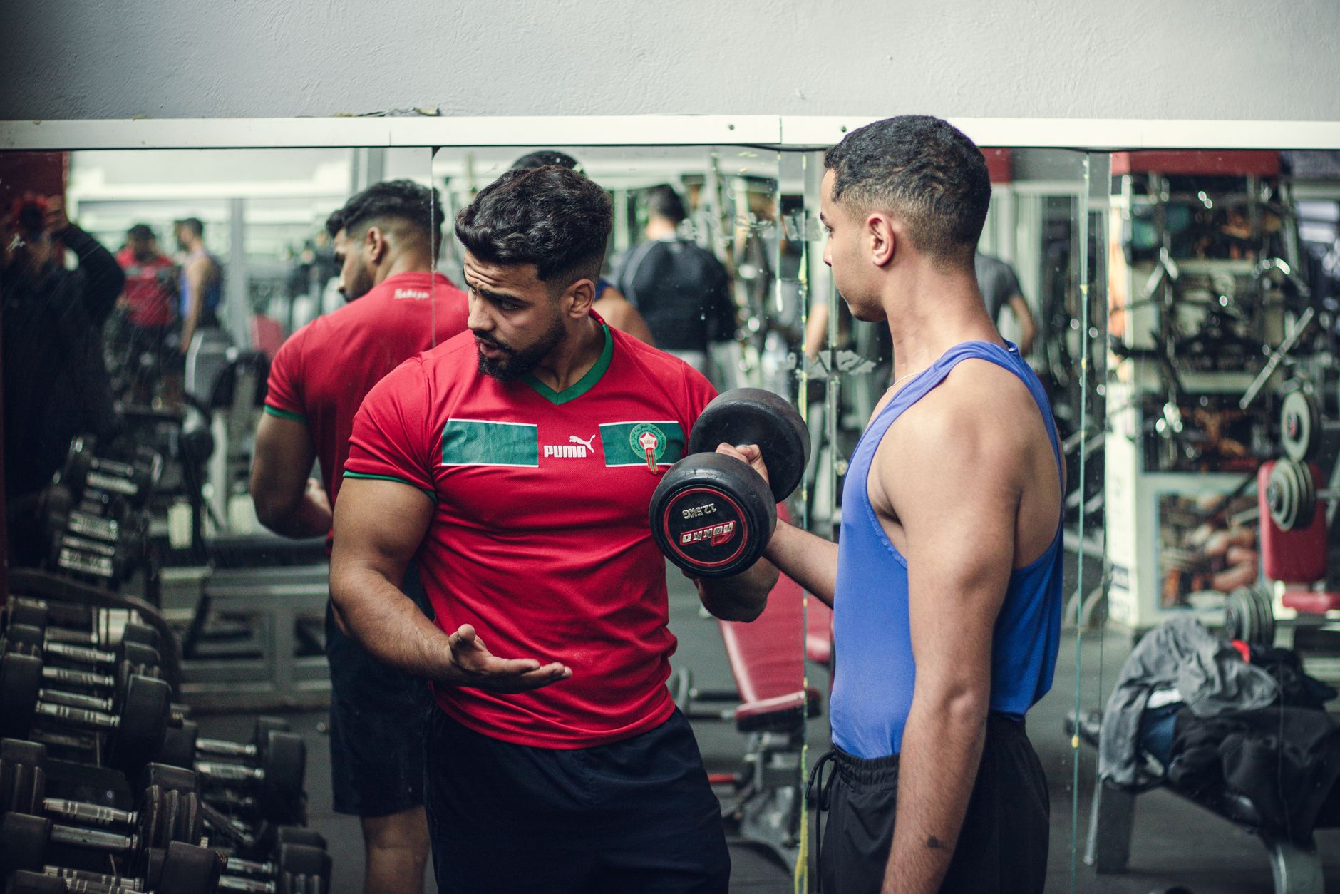 A trainer coaching a client through a dumbbell exercise in a gym