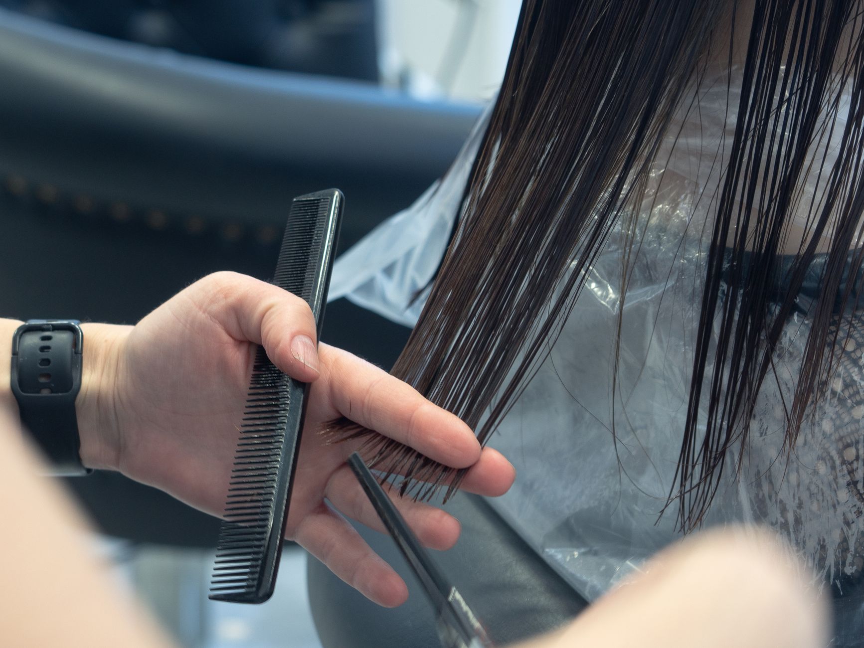 A stylist combing a section of wet hair before styling