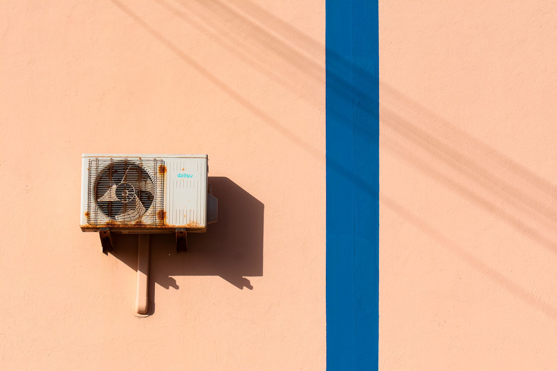 A weathered air conditioner condenser mounted on the exterior wall of a building