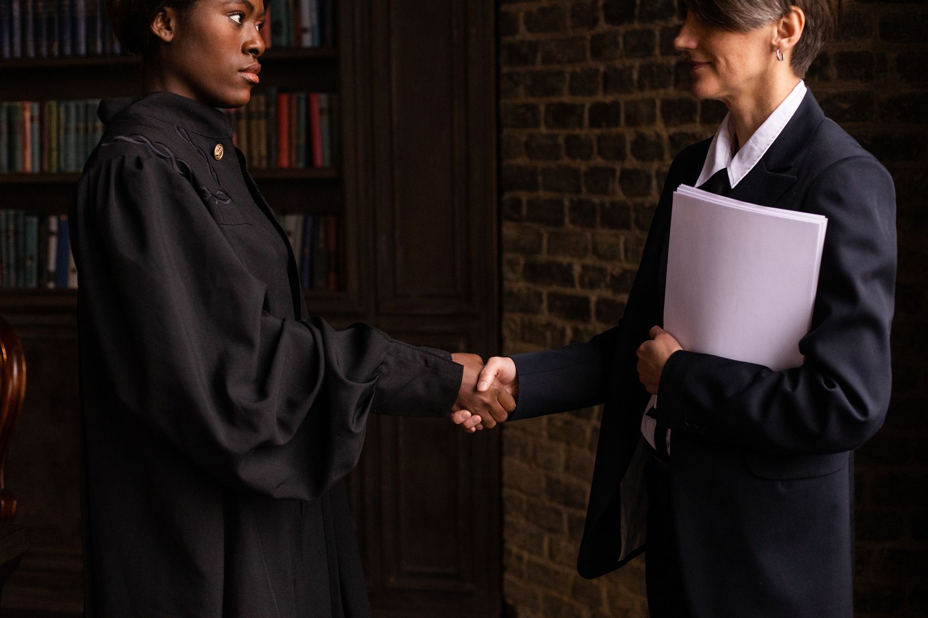 Two legal professionals shaking hands in a law office library